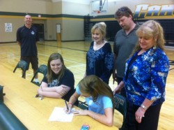 Amber Ramsey signs on the dotted line as Family looks on.