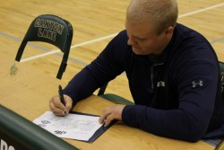 Austin Kahil working on his penmanship as he signs for East Texas Baptist University.